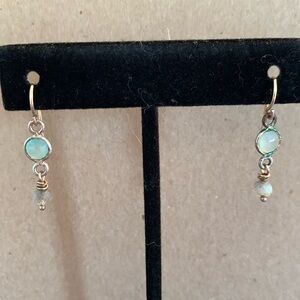 Delicate drop earring with light, green stone, gold metal.